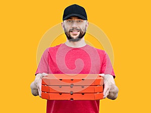 Smiling pizza delivery man holding out pizza boxes on a yellow background. Pizza delivery. Selective focus