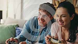 Smiling players enjoy video games sitting couch close up. Couple playing online