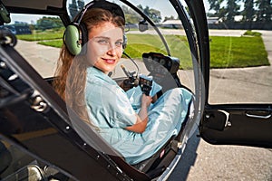 Joyous airwoman sitting in helicopter cabin before flight