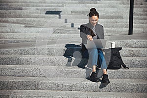 Smiling pleased freelancer sitting on the concrete steps