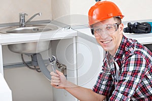 Smiling plumber near the kitchen sink