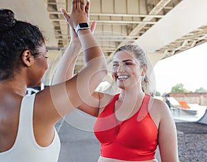 Smiling plus-size woman giving five to her fitness buddy