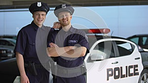 Smiling police mates greeting and looking at camera against squad car background