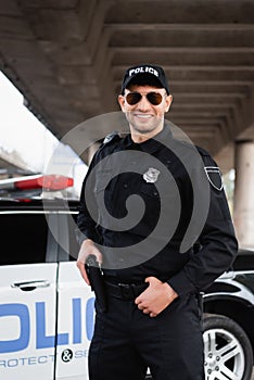 Smiling police officer in sunglasses holding