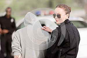 smiling policewoman in sunglasses with arrested