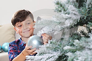 Smiling portrait child decorate the christmas tree with balls at home