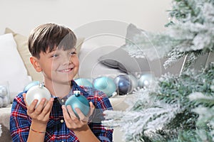 Smiling portrait child decorate the christmas tree with balls at home
