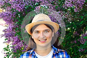 Smiling portrait. Defocus beautiful young woman near blooming spring tree. Bush lilac flowers. Youth, love, fashion