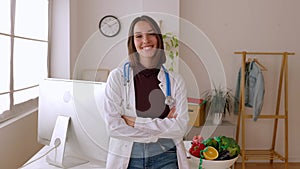 Smiling portrait of young female nutritionist doctor standing at desk office