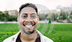 Smiling portrait of young gen z man looking at camera outdoors.