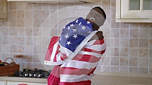 Smiling positive African American man wrapping in USA flag looking away. Portrait of happy patriotic young millennial