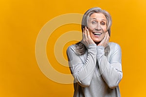 Smiling positive female with attractive look, posing against yellow blank wall. Happy woman showing positive emotions