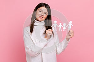 Smiling positive girl holds white paper family chain, looking at camera with happy facial expression