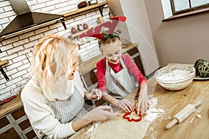 Smiling positive little child in striped apron learning cooking aspects