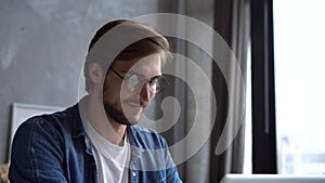 Smiling positive professional businessman working on laptop computer at home