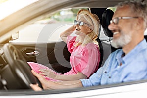 Smiling positive senior couple going summer vacation by car