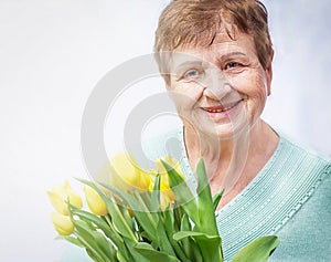 Smiling, positive senior (elderly) woman (over the age of 50) with bunch of flowers. Healthy grandmother. photo