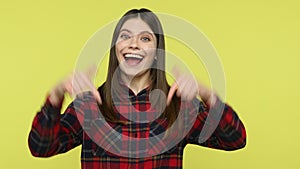 Smiling positive woman pointing fingers down showing thumbs up, asking to subscribe