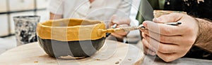 Smiling potters in aprons coloring ceramic