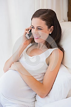 Smiling pregnancy phoning in his bed