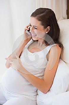 Smiling pregnancy phoning in his bed