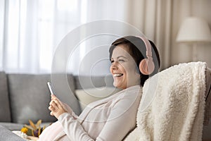 Smiling pregnant female listen to music in earphones