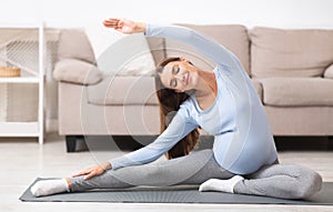 Smiling pregnant girl doing stretching exercises on mat