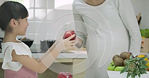 Smiling pregnant mother and daughter enjoys being in the kitchen together