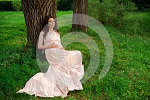Smiling pregnant woman 25-29 year old resting by the lake. Posing outdoors. Motherhood. Maternity.