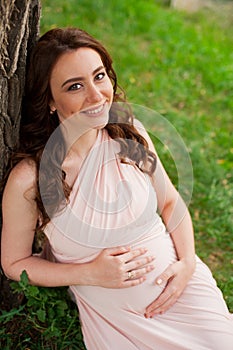 Smiling pregnant woman 25-29 year old resting by the lake. Posing outdoors. Motherhood. Maternity.