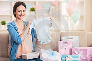 Smiling Pregnant Woman with Blue Baby Romper.