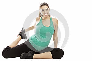 A smiling pregnant woman, brunette, performs physical exercises on the floor. Isolated on a white background. Place for text