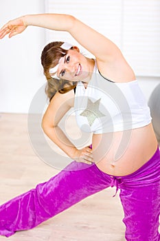 Smiling pregnant woman doing stretching exercises