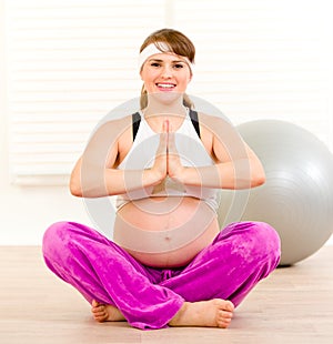 Smiling pregnant woman doing yoga exercises