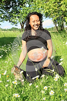 Smiling pregnant woman with drawing of baby on belly and cat