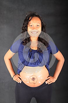 Smiling pregnant woman with drawing of sperms reaching egg on belly