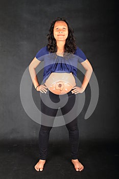 Smiling pregnant woman with drawing of sperms reaching egg on belly