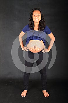 Smiling pregnant woman with drawing of sperms reaching egg on belly