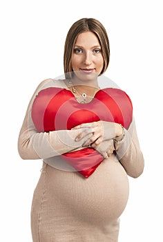 Smiling pregnant woman with heart shaped pillow