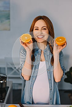 smiling pregnant woman holding cut oranges
