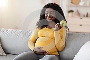 Smiling pregnant woman holding green apple, copy space