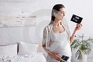 smiling and pregnant woman holding ultrasound