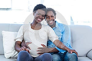 Smiling pregnant woman with husband sitting at home