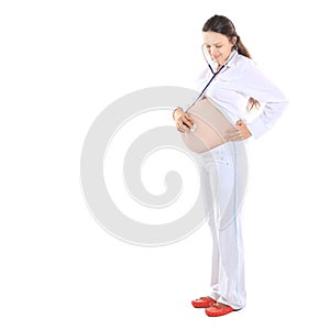 Smiling pregnant woman listening to baby`s heartbeat using a stethoscope.