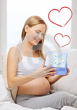 Smiling pregnant woman opening gift box
