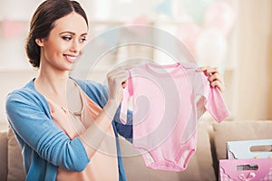 Smiling Pregnant Woman with Pink Baby Romper.