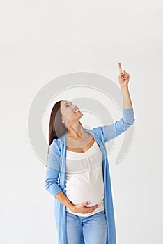 Smiling pregnant woman pointing finger upwards