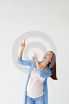 Smiling pregnant woman pointing upwards with fingers