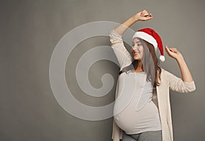 Smiling pregnant woman in Santa hat at studio