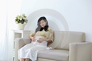 Smiling pregnant woman sitting on sofa